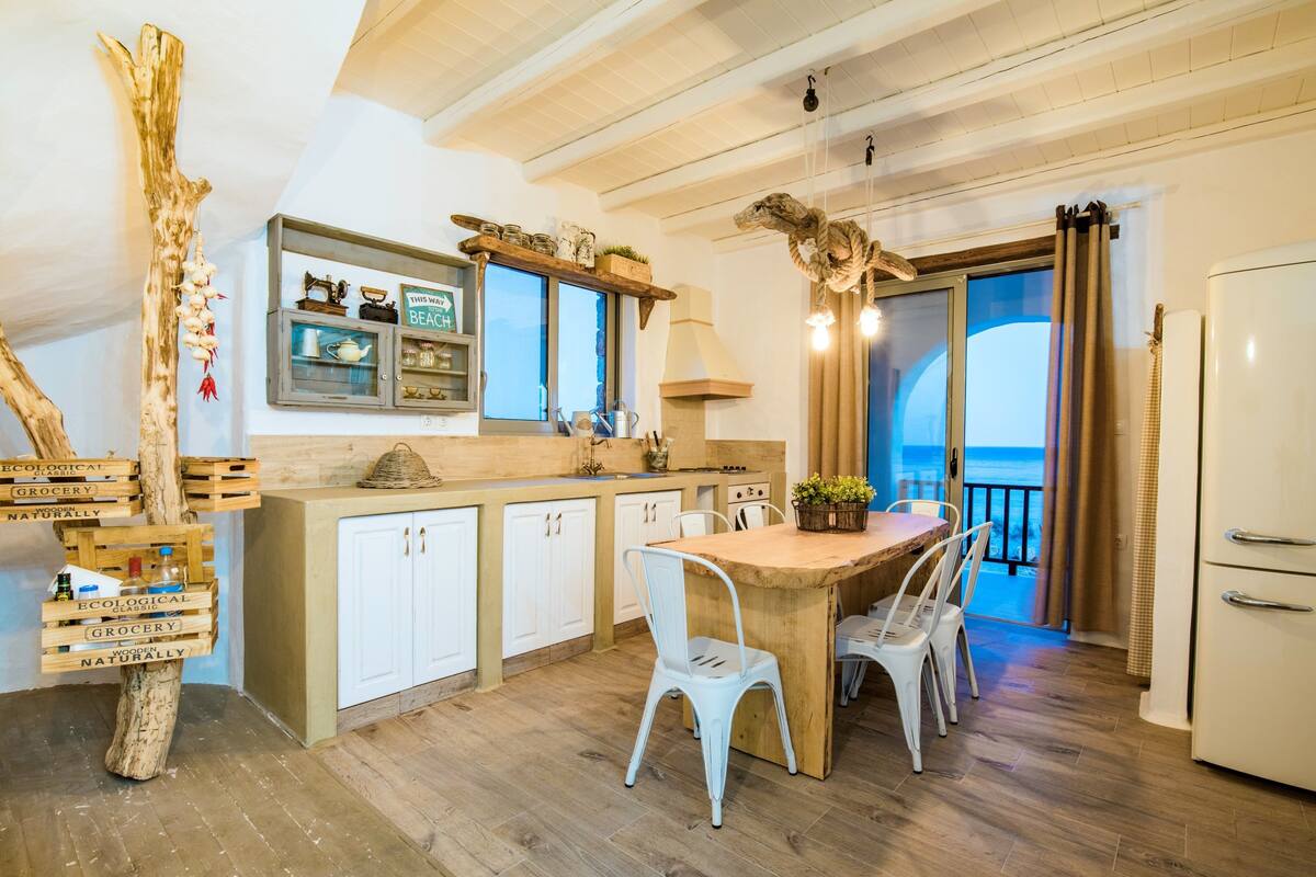 A kitchen with a wooden island, white cabinets, and a view to the outside.
