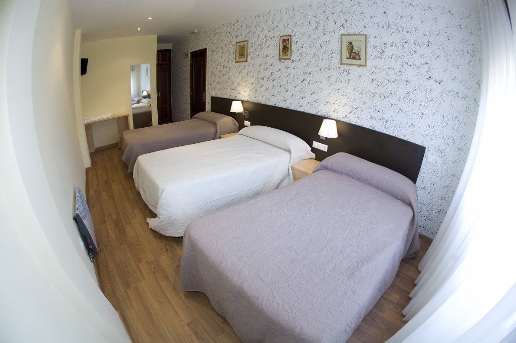 Habitación de hotel con dos camas individuales, un escritorio y un espejo.