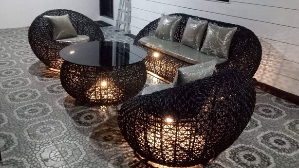 Et moderne loungeområde med et rundt glasbord omgivet af bløde siddepladser.