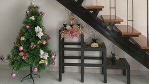 En trappe med trætrin og metalgelændere, pyntet med festlige dekorationer og et juletræ.