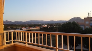 A balcony with a view of a residential area, mountains, and a building with antennas.