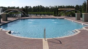 Ein rechteckiger Swimmingpool mit Tauchbrett in der Mitte, umgeben von einer Ziegelterrasse.