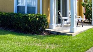 Ein zweistöckiges Haus mit überdachter Veranda und einem kleinen Garten.