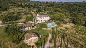 An aerial view of a large villa with a swimming pool, surrounded by well-maintained gardens and vineyards. - Country House Villa Rey (Panicale)