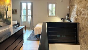 A bedroom with a bed, a desk, and a dresser. There are two windows and a door. - Forcalquier Architecture Village House Center (Forcalquier)