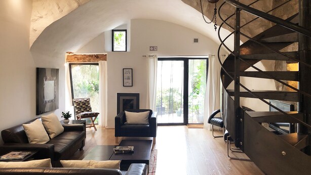 A spacious living room with a high ceiling, a staircase, and large windows allowing natural light. - Forcalquier Architecture Village House Center (Forcalquier)