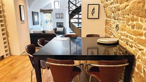 A dining area with a long table, chairs, and a stone wall. - Forcalquier Architecture Village House Center (Forcalquier)