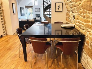 A dining area with a long table, chairs, and a stone wall. - Forcalquier Architecture Village House Center (Forcalquier)