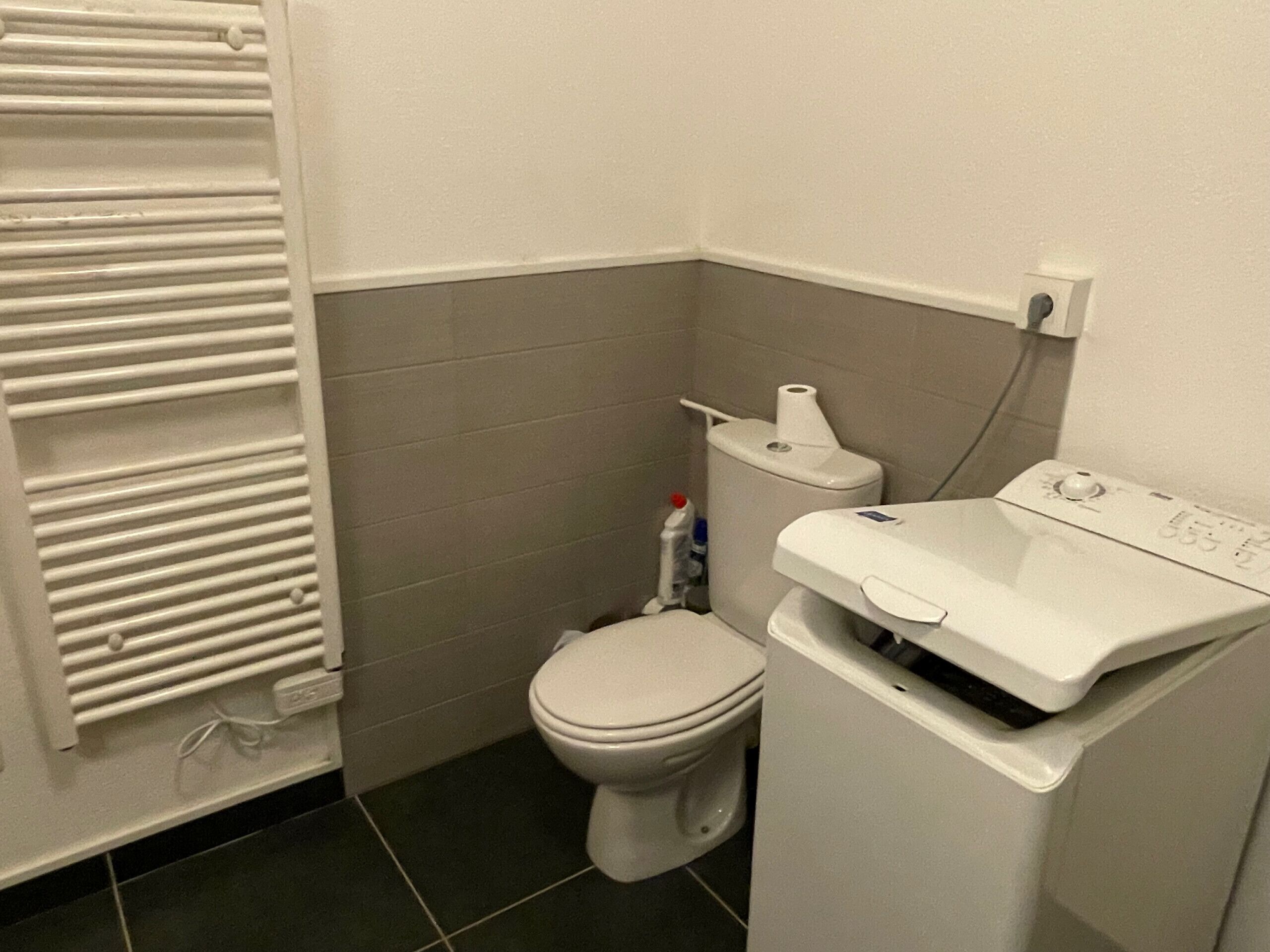 Un baño pequeño con inodoro, lavadora y radiador.