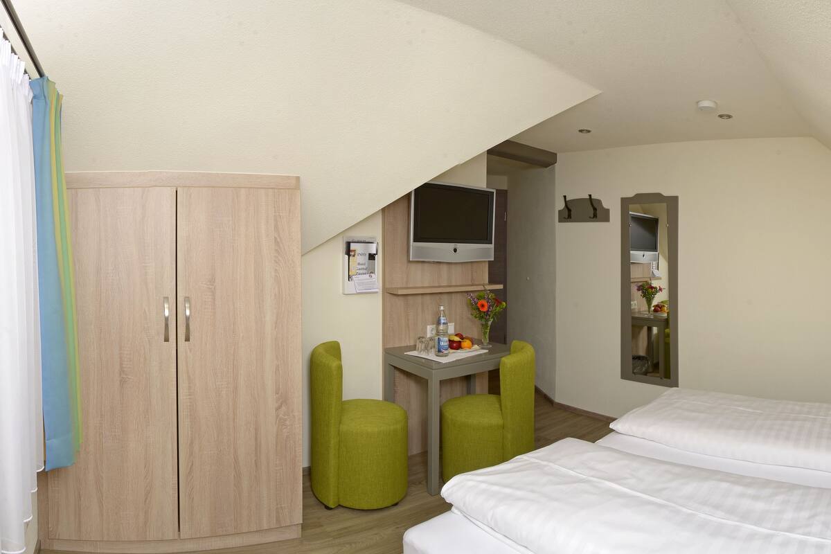 Une chambre d’hôtel avec deux lits, un bureau, un miroir et une armoire.