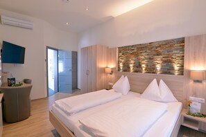 Ein modernes Hotelzimmer mit einem großen Bett, einem Schreibtisch und einem Fernseher.