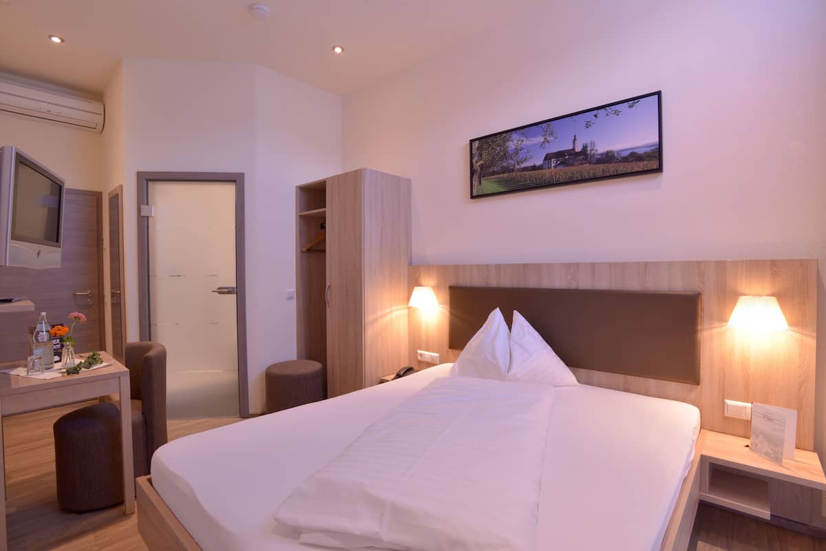 Une chambre d’hôtel avec un lit, une table de chevet, une lampe et un tableau au mur.