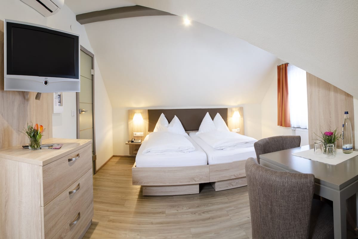 Une chambre d’hôtel moderne équipée d’un grand lit, d’un bureau, d’une chaise, d’une télévision et d’un miroir.
