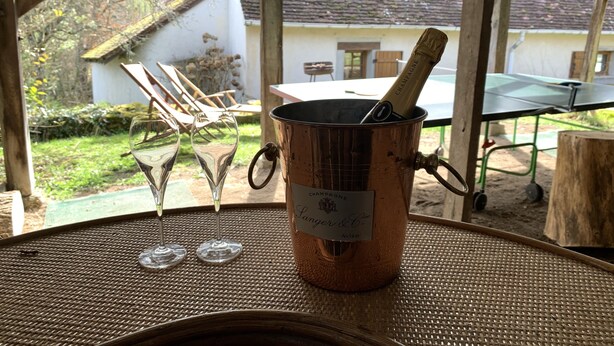 A table with a copper champagne bucket, two empty wine glasses, and a bottle of champagne. - Private detached stone house overlooking a lake (Sazeray)
