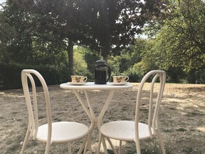 A table with two chairs, a coffee pot, and two cups. - Private detached stone house overlooking a lake (Sazeray)