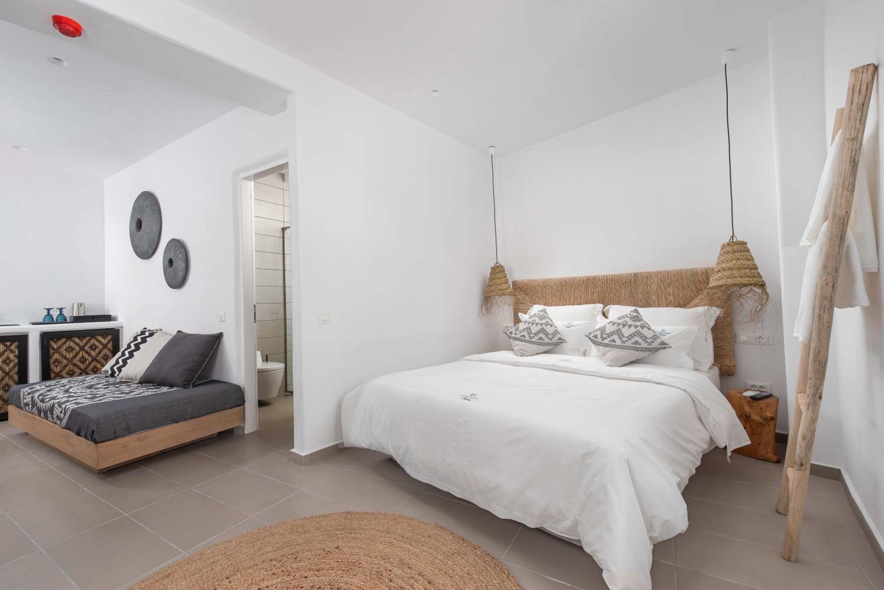 Une chambre à coucher moderne avec un grand lit, un petit canapé et une tête de lit en bois.