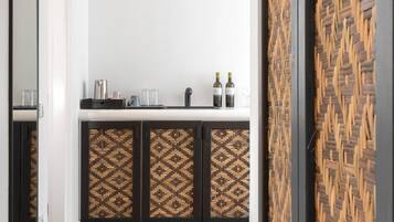 A modern kitchen with a white countertop, two patterned cabinets, and a woven wall.