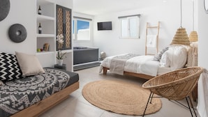 Een moderne slaapkamer met een slaapbank, twee bedden, een televisie en een balkon met uitzicht.
