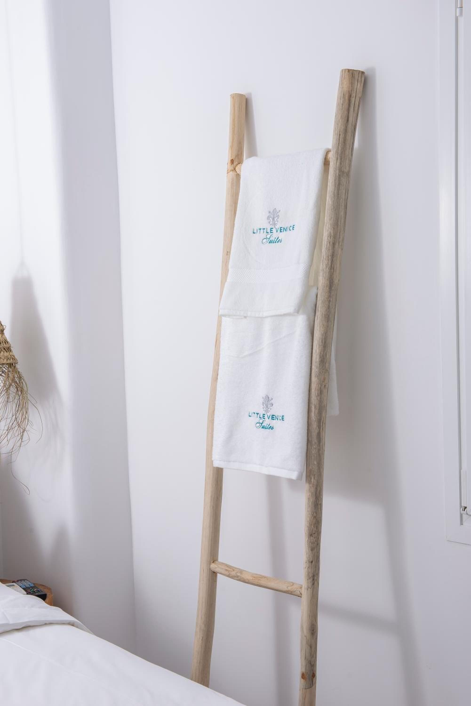 A wooden ladder with two white towels hanging on it, each with embroidered text.