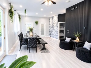 Un espace repas moderne avec une longue table, des chaises noires et des plantes suspendues.