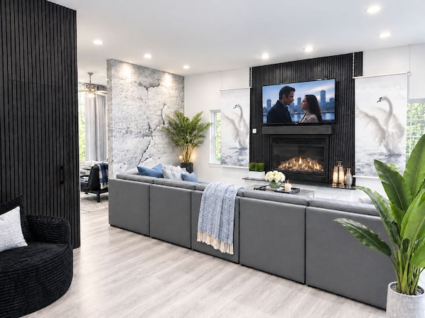 Un salon moderne doté d’un grand téléviseur, d’une cheminée et d’un espace détente.