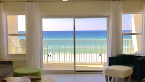 A spacious living room with a large sliding glass door leading to a balcony with a view of the ocean. - Beachfront Condo, 1 King Bedroom + Bunk, 2 baths, sleeps 5 (Destin)