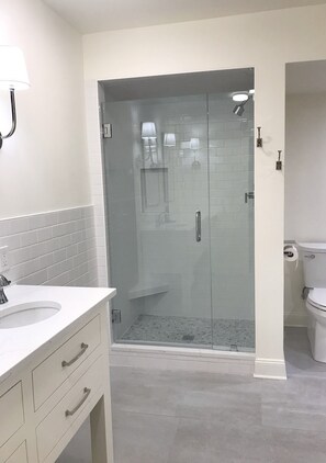 Une salle de bain moderne avec une douche à parois de verre, un lavabo blanc et des toilettes.