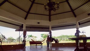 A covered outdoor area with a tiled floor, a hammock, and a table with fruits. - Hotel Rio Humadea (Guamal)