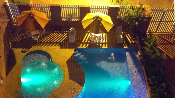 An outdoor swimming pool with a wooden deck and umbrellas. - Hotel Rio Humadea (Guamal)