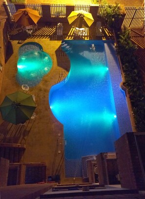 An outdoor swimming pool with a wooden deck and umbrellas.