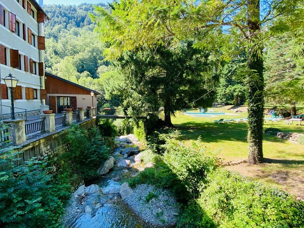 A riverside view with a bridge, lush greenery, and a swimming area. - Hotel Vall Fosca (La Torre de Cabdella)