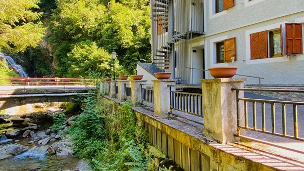 A building with balconies and a river in front. - Hotel Vall Fosca (La Torre de Cabdella)