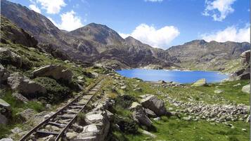 Un paisaje montañoso con un lago azul cristalino y una vía de tren que lo atraviesa.