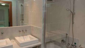 Un baño moderno con dos lavamanos, cabina de ducha de vidrio y un espejo.