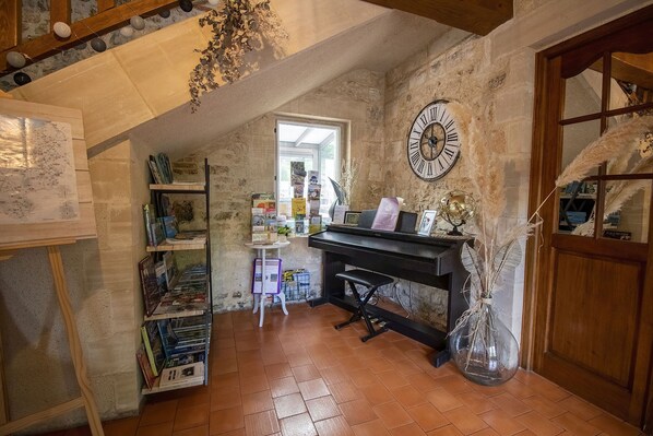 Un rincón acogedor para leer con un piano, estanterías y un gran reloj de pared.