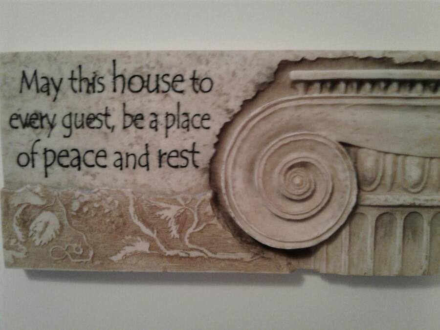 Una pieza decorativa con una cita sobre la paz y el descanso, y un diseño de columna clásica.