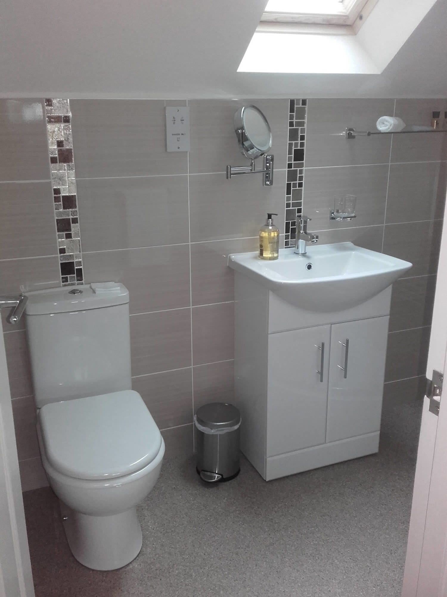 Een badkamer met toilet, wastafel en spiegel.