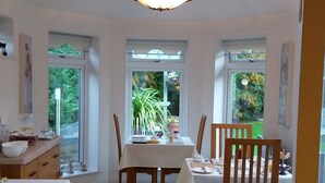 Un coin repas avec une table dressée pour quatre personnes, entourée de chaises, et un lustre au-dessus.