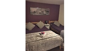 A bedroom with two beds, a nightstand, and a zebra artwork on the wall. - Hathway House (Bristol)