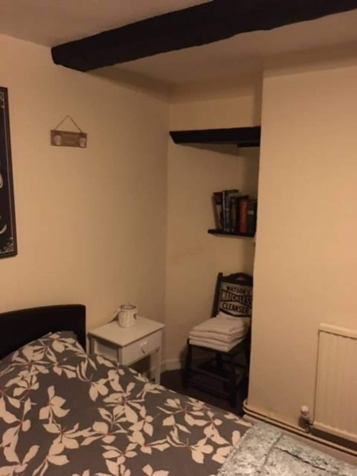 A bedroom with a bed, a bedside table, a chair, and a radiator.