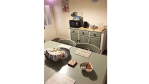 A dining area with a table set for two, a microwave, and a small cabinet with drawers. - Hathway House (Bristol)