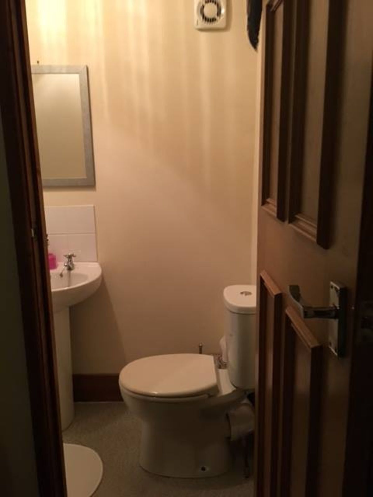 A small, compact bathroom with a toilet, sink, and a mirror.