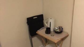 A small, compact room with a single bed, a bedside table with a lamp, and a TV mounted on the wall.