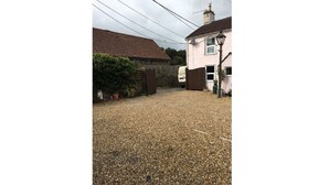 A gravel driveway leading to a house with a red-tiled roof and a pink exterior wall. - Hathway House (Bristol)