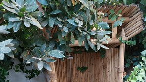 A bamboo shower enclosure with a showerhead and a small pool of white pebbles at the bottom.