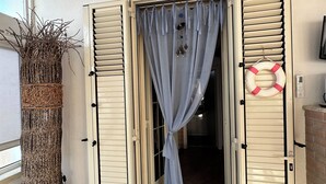 An open door with a blue curtain, a life preserver on the wall, and a tall woven basket on the left.