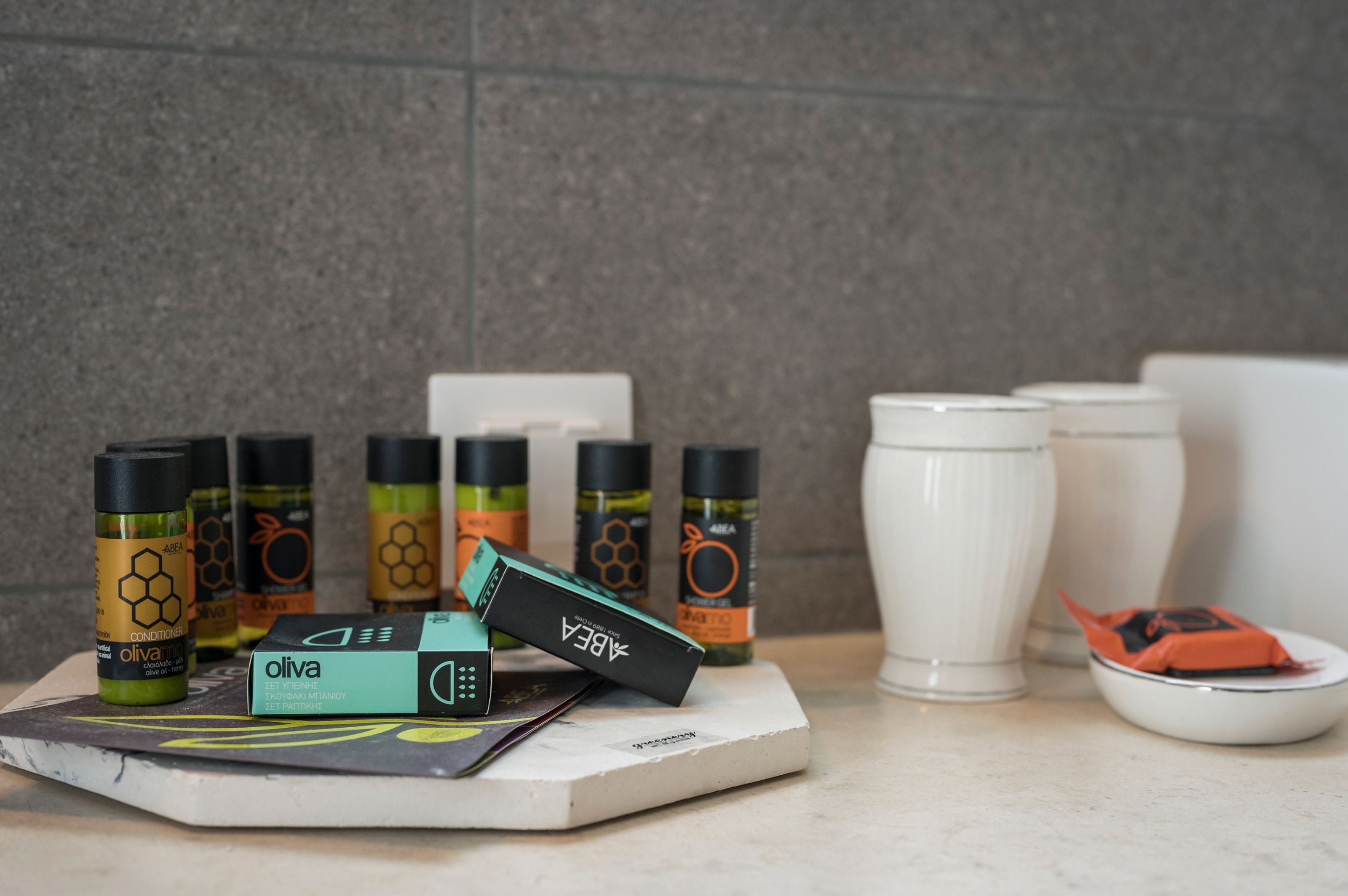 A countertop with various olive oil bottles, a box, and a white ceramic cup.