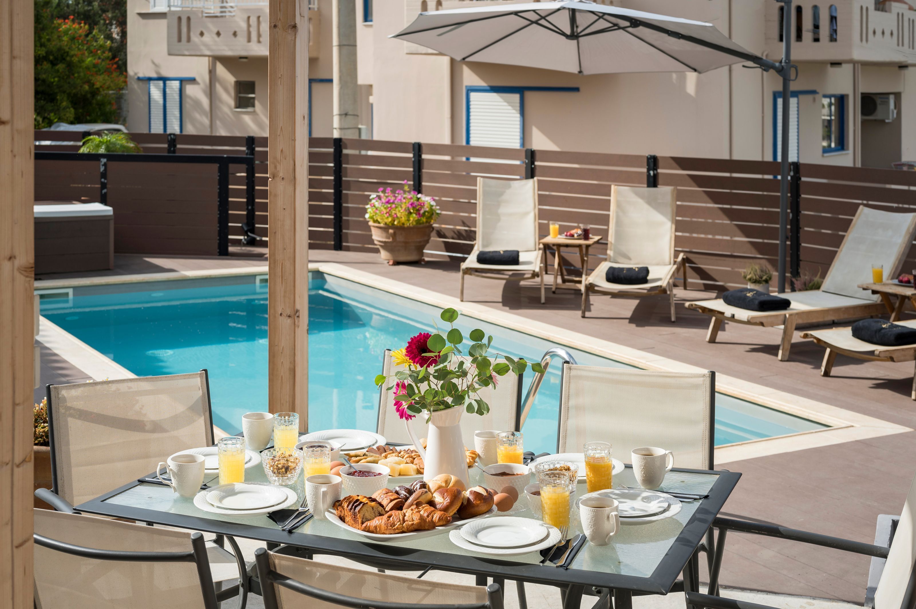 Café da manhã à beira da piscina com mesa, cadeiras e vista para a piscina.