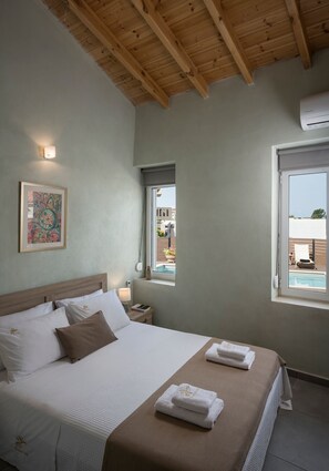 Ein Schlafzimmer mit Bett, Nachttisch, Fenster und Holzbalkendecke.