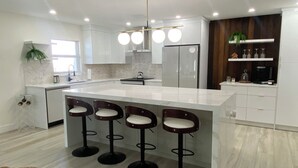 Una cocina moderna con una isla central, taburetes de bar y un refrigerador integrado.